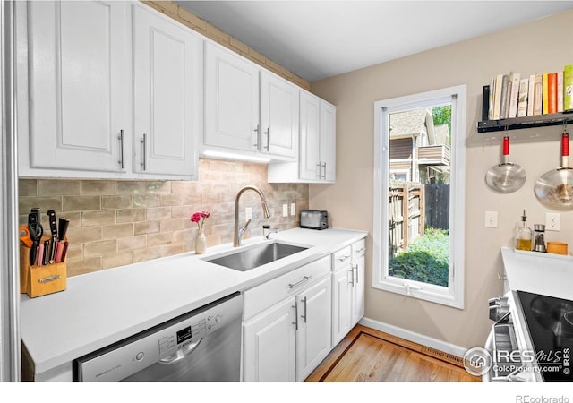 kitchen featuring appliances with stainless steel finishes, a sink, light wood-style flooring, tasteful backsplash, and baseboards