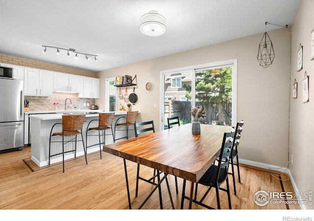 dining area featuring light wood finished floors and baseboards