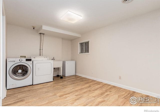 laundry area featuring independent washer and dryer, light wood-style floors, and baseboards