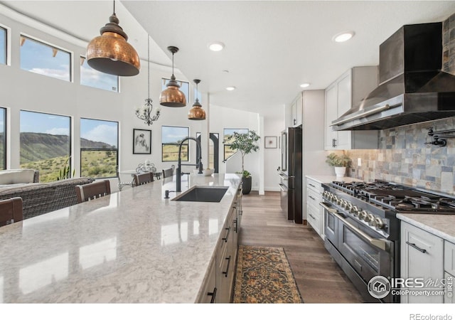 2118 Dry Creek Dr, Lyons, CO 80540 - kitchen with appliances with stainless steel finishes, wall chimney range hood, a sink, tasteful backsplash, and dark wood finished floors