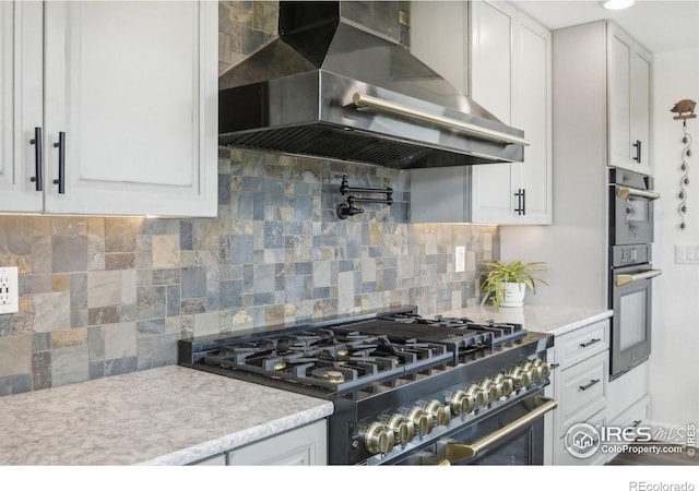2118 Dry Creek Dr, Lyons, CO 80540 - kitchen featuring wall chimney range hood, appliances with stainless steel finishes, white cabinetry, light countertops, and tasteful backsplash