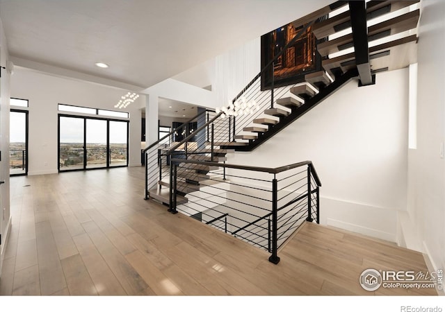 stairs with wood finished floors, baseboards, and recessed lighting