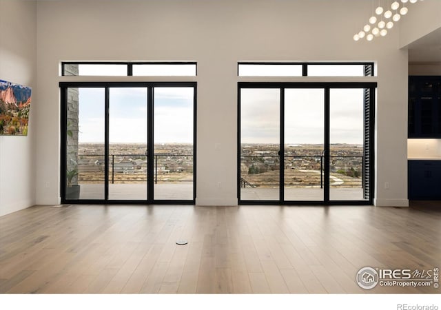 unfurnished room with wood finished floors, plenty of natural light, and a high ceiling