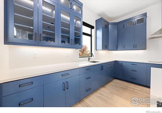 kitchen featuring blue cabinetry, light wood-style flooring, decorative backsplash, and light countertops