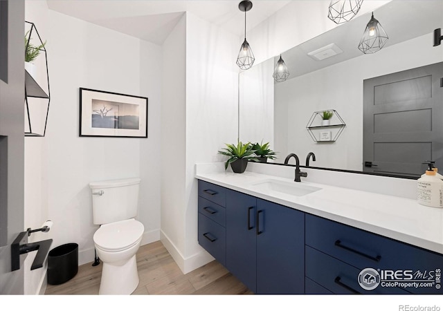 bathroom with wood finished floors, toilet, baseboards, and vanity