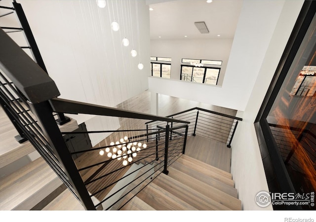 stairs featuring wood finished floors and recessed lighting