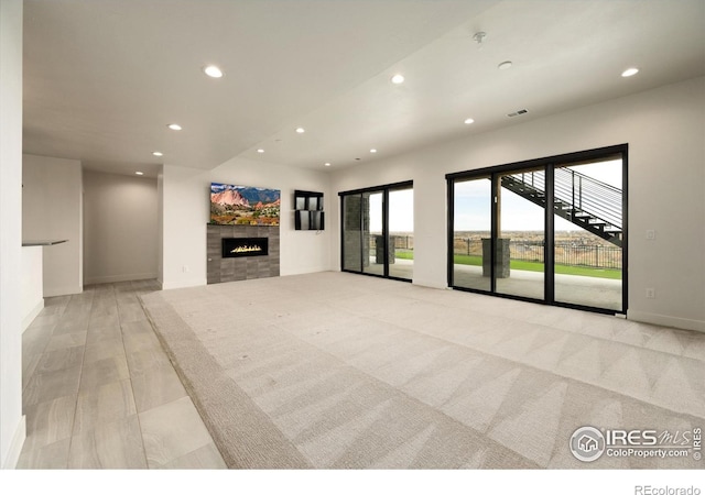 unfurnished living room with recessed lighting, a tiled fireplace, and baseboards