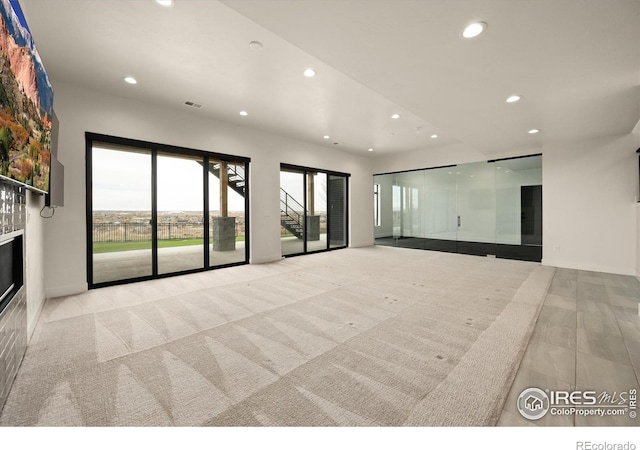 unfurnished living room featuring recessed lighting, a glass covered fireplace, and baseboards