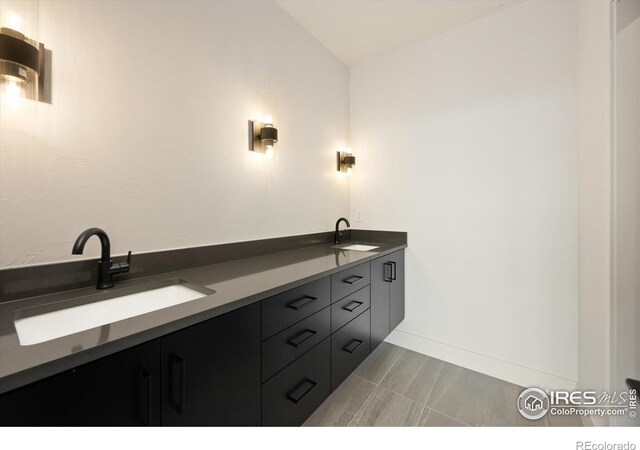 full bathroom with lofted ceiling, baseboards, and double vanity
