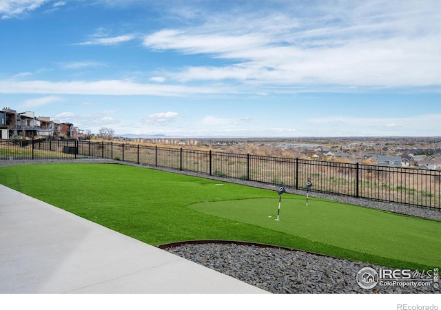 view of yard featuring a putting area, fence, and a residential view