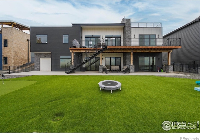 back of house with stairs, a patio area, an outdoor fire pit, a putting green, and an attached garage