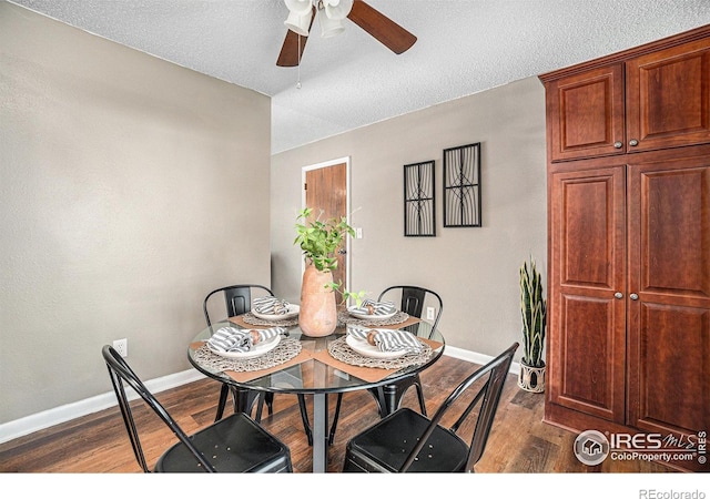 dining space featuring ceiling fan, dark wood-style flooring, baseboards, and a textured ceiling