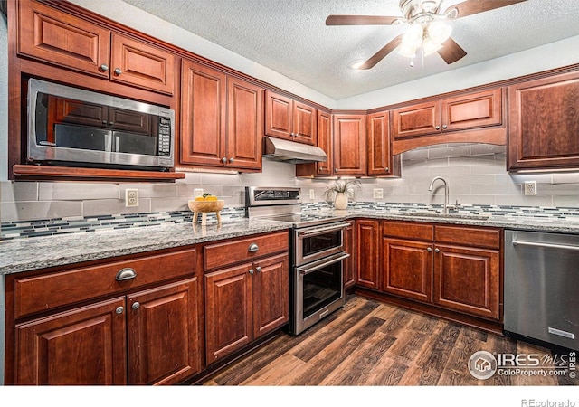 kitchen featuring appliances with stainless steel finishes, a sink, under cabinet range hood, dark wood-style floors, and ceiling fan