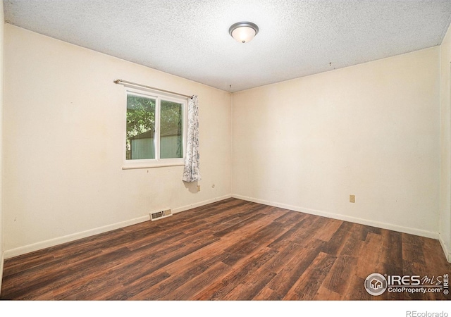 spare room with dark wood finished floors, baseboards, and a textured ceiling