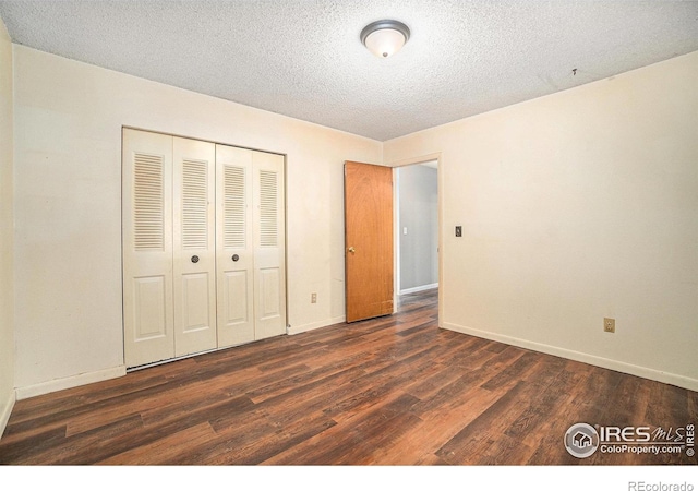 unfurnished bedroom featuring dark wood-style floors, baseboards, a closet, and a textured ceiling
