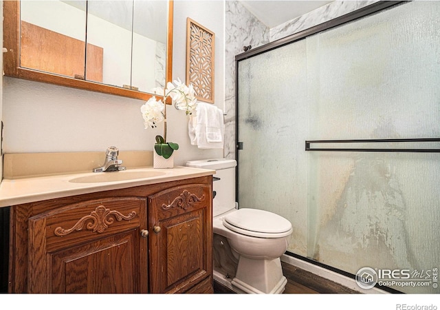 full bathroom featuring a shower stall, toilet, vanity, and wood finished floors