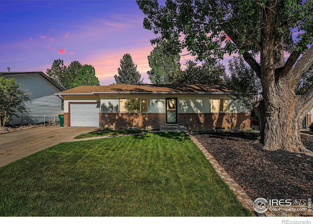 ranch-style home featuring brick siding, a garage, concrete driveway, and a front lawn