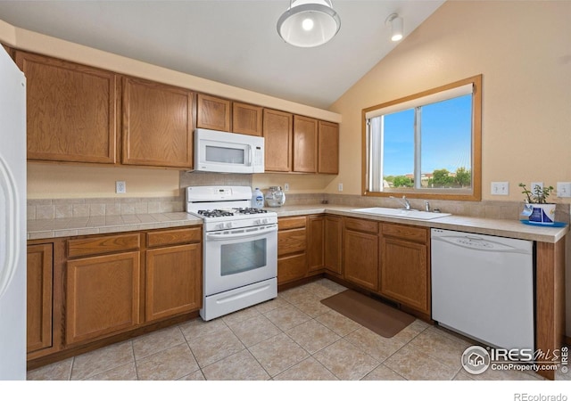 3949 Willowood Ave, Loveland, CO 80538 - kitchen featuring white appliances, a sink, vaulted ceiling, brown cabinetry, and light tile patterned floors