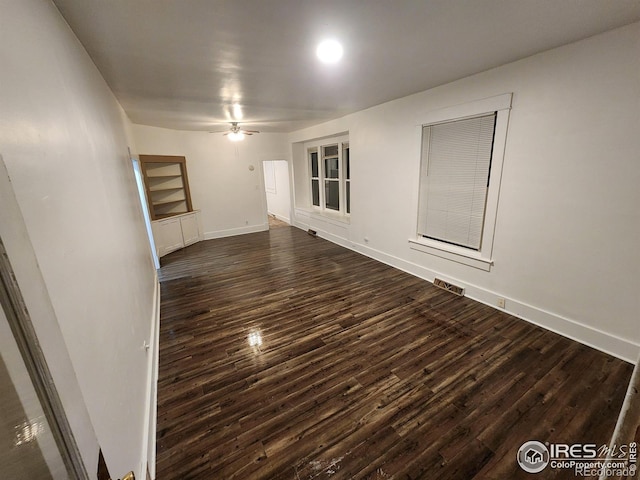 empty room with dark wood-style flooring, ceiling fan, and baseboards