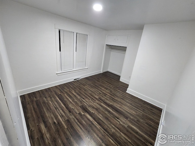 unfurnished bedroom featuring dark wood-style floors, baseboards, and a closet