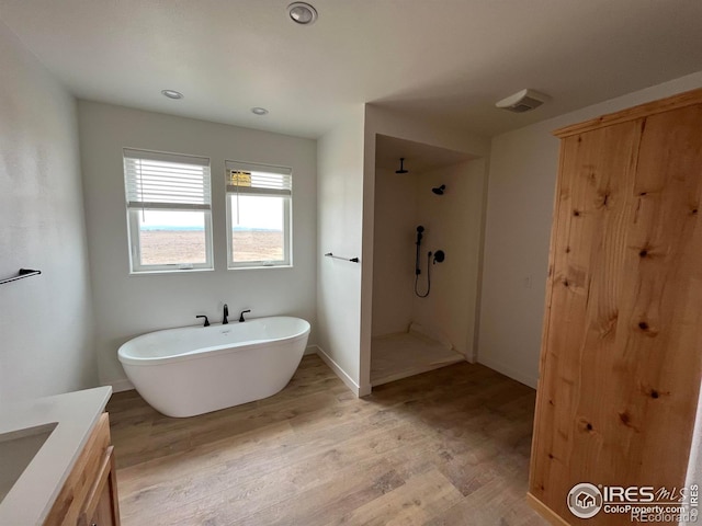full bath featuring wood finished floors, walk in shower, a soaking tub, vanity, and recessed lighting