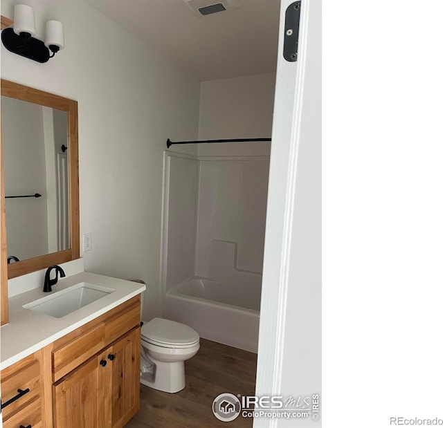 full bathroom featuring wood finished floors, toilet, vanity, and bathtub / shower combination