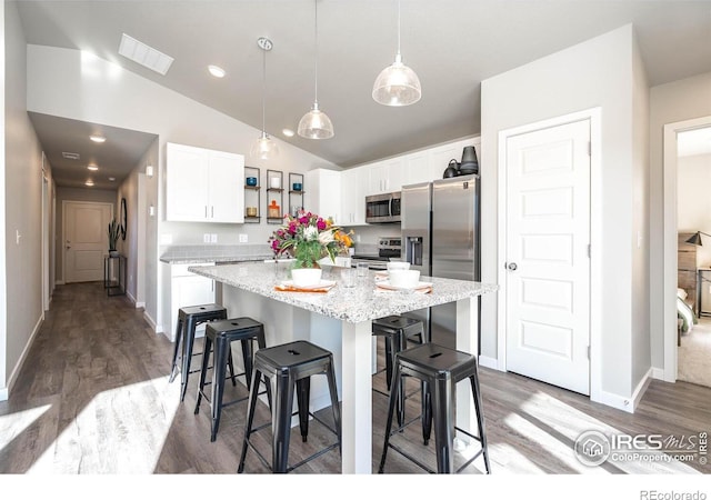 7179 Gateway Crossing St, Wellington, CO 80549 - kitchen with appliances with stainless steel finishes, open shelves, white cabinets, a kitchen bar, and vaulted ceiling