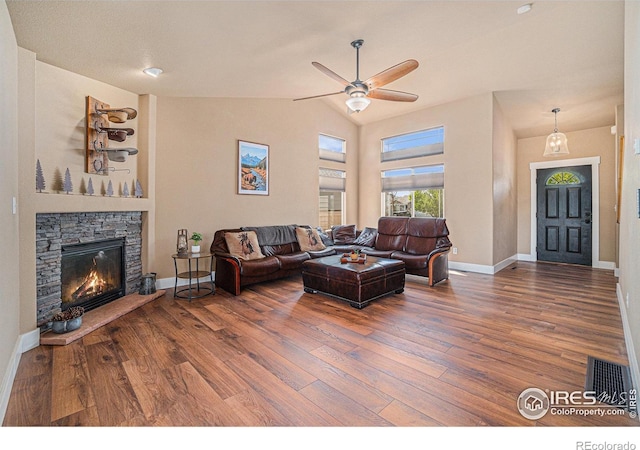 8962 Smoke Signal Way, Wellington, CO 80549 - living room with wood finished floors, a ceiling fan, vaulted ceiling, baseboards, and a stone fireplace