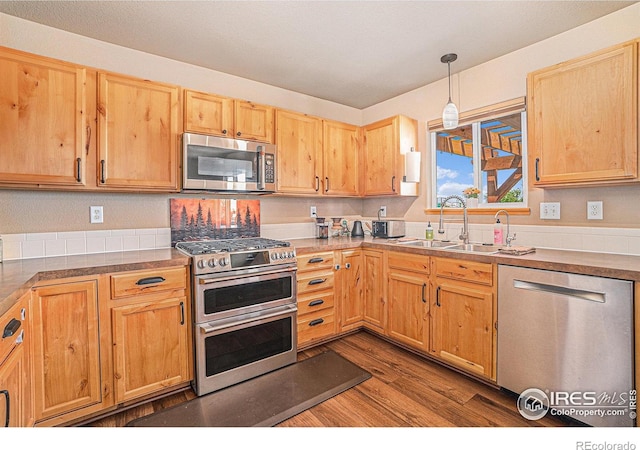 8962 Smoke Signal Way, Wellington, CO 80549 - kitchen featuring appliances with stainless steel finishes, a sink, dark wood finished floors, pendant lighting, and light countertops