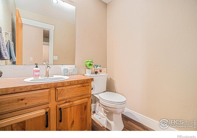 8962 Smoke Signal Way, Wellington, CO 80549 - bathroom featuring toilet, vanity, baseboards, a textured wall, and wood finished floors