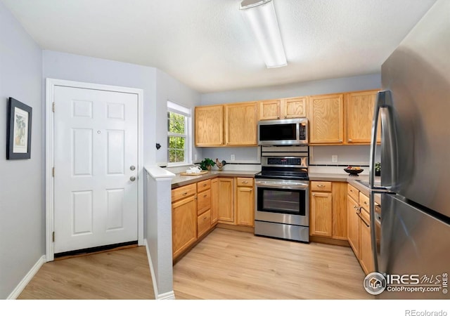 1014 Andrews Peak Dr Unit B107, Fort Collins, CO 80521 - kitchen with appliances with stainless steel finishes, light wood-style floors, light countertops, and light brown cabinetry