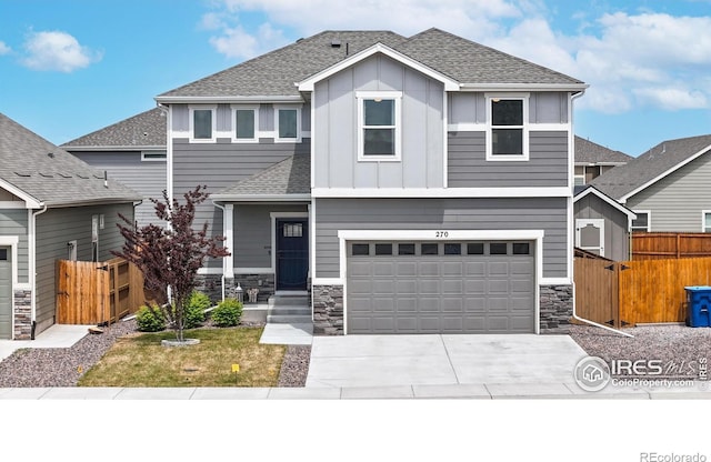 view of front of property featuring fence, driveway, stone siding, and an attached garage