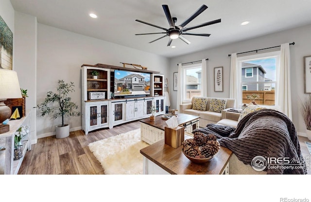 living area featuring wood finished floors, a ceiling fan, recessed lighting, and baseboards