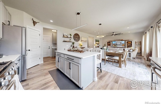kitchen with a breakfast bar area, light wood-style floors, high end range, light countertops, and recessed lighting
