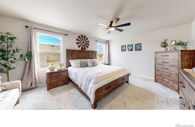 bedroom featuring light colored carpet, a ceiling fan, and baseboards