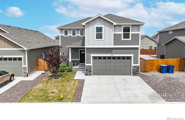 view of front of property with stone siding, fence, board and batten siding, and concrete driveway