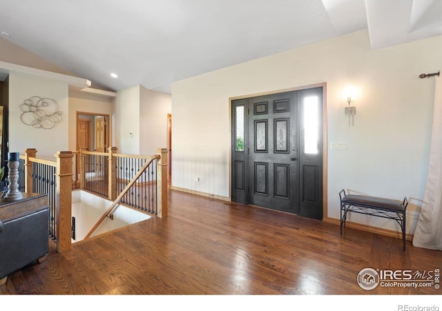 foyer featuring wood finished floors, vaulted ceiling, and baseboards