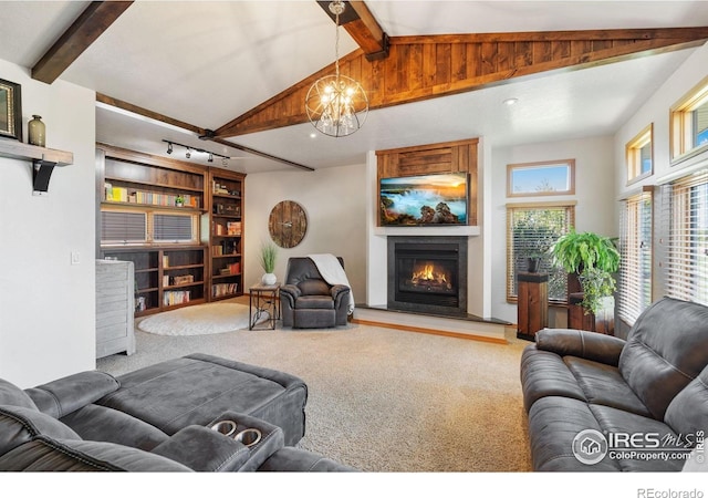 living room with carpet, a chandelier, a lit fireplace, and built in shelves