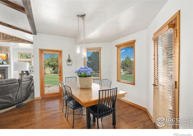 dining room with wood finished floors, a warm lit fireplace, baseboards, and beam ceiling