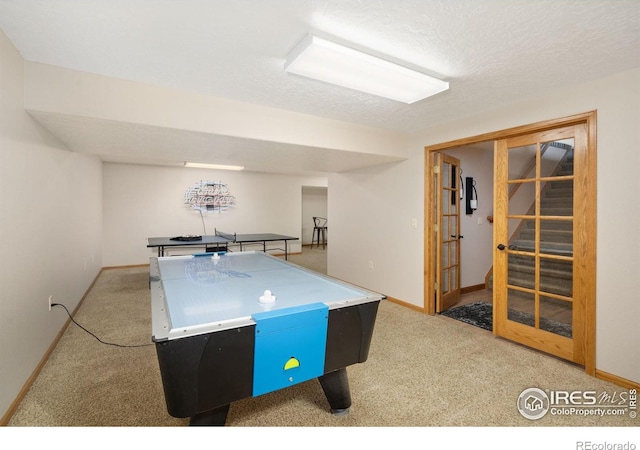 recreation room with carpet floors, baseboards, and a textured ceiling