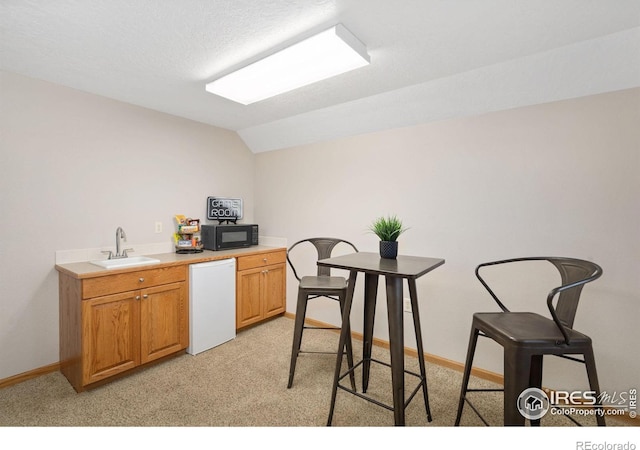 kitchen featuring a sink, black microwave, dishwasher, light colored carpet, and light countertops