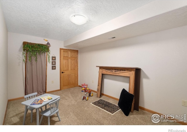 rec room with carpet flooring, baseboards, and a textured ceiling