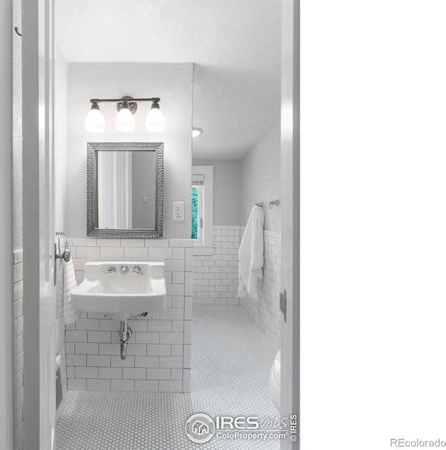 721 9th St, Boulder, CO 80302 - bathroom with tile walls, tile patterned floors, toilet, a wainscoted wall, and a sink