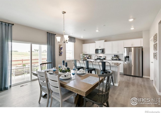 dining space with light wood-style flooring, a chandelier, recessed lighting, and baseboards