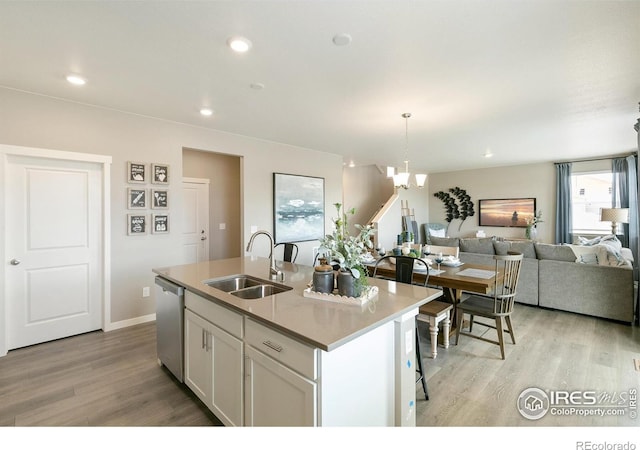 kitchen featuring a sink, dishwasher, light wood-type flooring, open floor plan, and a chandelier