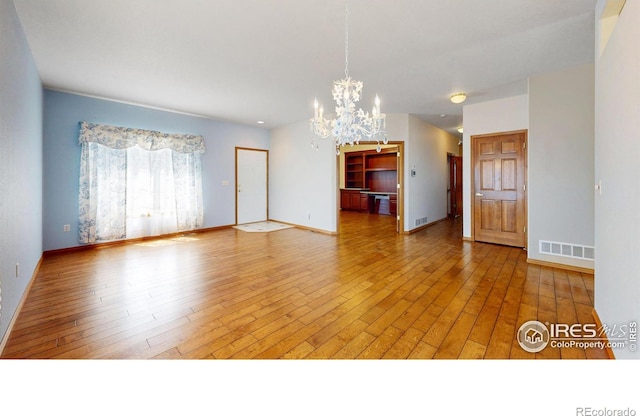 4447 Twin Peaks Dr, Loveland, CO 80537 - unfurnished living room featuring a chandelier, light wood finished floors, and baseboards