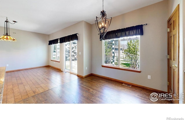 4447 Twin Peaks Dr, Loveland, CO 80537 - empty room featuring a chandelier, wood finished floors, and baseboards