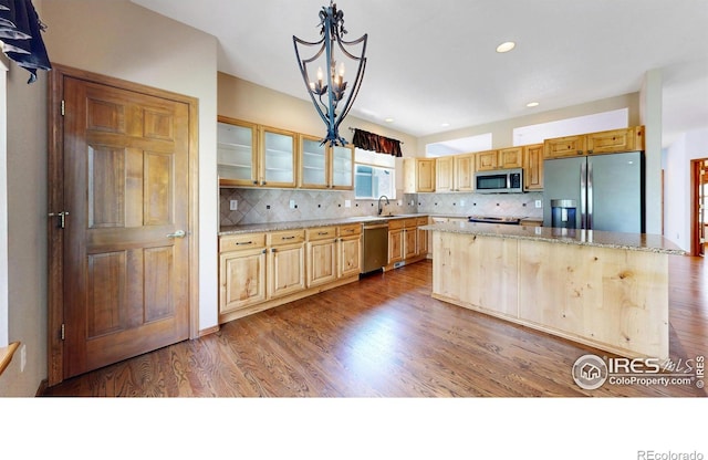 4447 Twin Peaks Dr, Loveland, CO 80537 - kitchen with appliances with stainless steel finishes, a center island, glass insert cabinets, light stone counters, and a chandelier