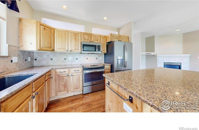 4447 Twin Peaks Dr, Loveland, CO 80537 - kitchen with stainless steel appliances, light brown cabinets, light wood-type flooring, light stone counters, and tasteful backsplash