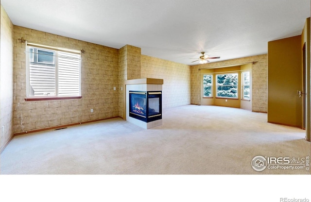 4447 Twin Peaks Dr, Loveland, CO 80537 - unfurnished living room with a ceiling fan, a multi sided fireplace, carpet, and brick wall